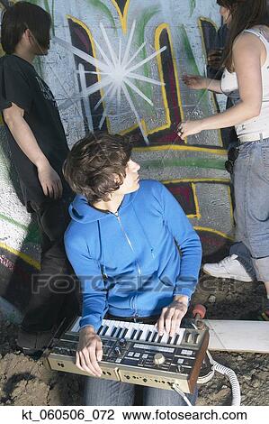 Stock Image - Group of young adults next to graffitied wall. Fotosearch