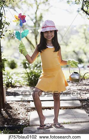 Hispanic girl holding flower pinwheel and watering can outdoors View Large Photo Image Stock Image - Hispanic girl holding flower pinwheel and watering can outdoors. Fotosearch