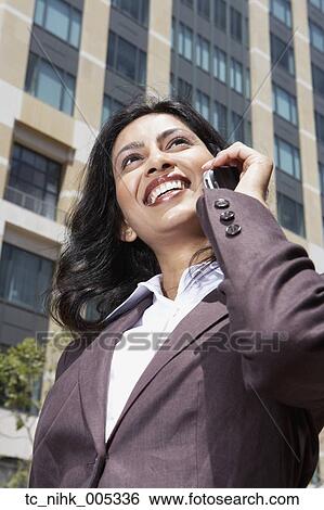Stock Photograph - Indian businesswoman using cell phone outdoors. Fotosearch