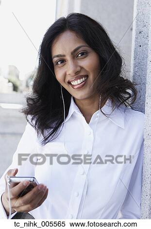 Stock Photography - Indian woman listening to mp3 player outdoors. Fotosearch