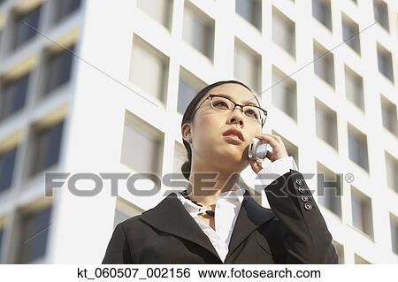 Low angle view of Asian businesswoman using cell phone View Large Photo Image Stock Photograph - Low angle view of Asian businesswoman using cell phone. Fotosearch