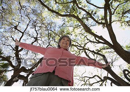 Low angle view of senior woman with arm outstretched outdoors View Large Photo Image Picture - Low angle view of senior woman with arm outstretched outdoors. Fotosearch