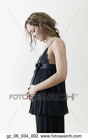 Pregnant woman in fancy clothing looking at stomach View Large Photo Image Stock Image - Pregnant woman in fancy clothing looking at stomach. Fotosearch
