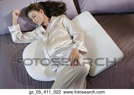 Stock Image - Pregnant woman sleeping with back and stomach pillows. Fotosearch