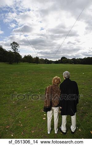 Picture - Rear view of senior couple looking out over open meadow. Fotosearch