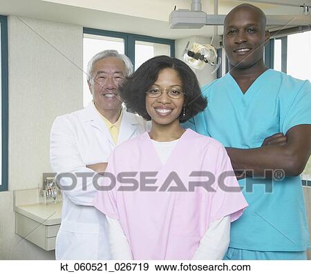 Stock Photo - Senior Asian male dentist with African male and female dental assistants. Fotosearch