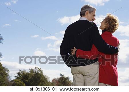 Stock Image - Senior couple smiling at each other outdoors. Fotosearch