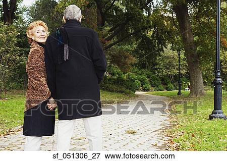 Senior couple walking and holding hands in park View Large Photo Image Stock Photo - Senior couple walking and holding hands in park. Fotosearch