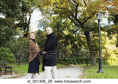 Senior couple walking and holding hands in park View Large Photo Image Stock Photo - Senior couple walking and holding hands in park. Fotosearch