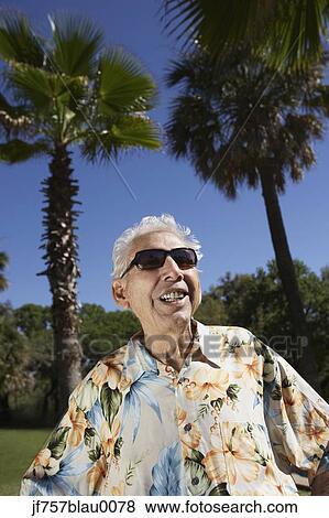 Stock Photo - Senior man wearing sunglasses and Hawaiian shirt outdoors. Fotosearch