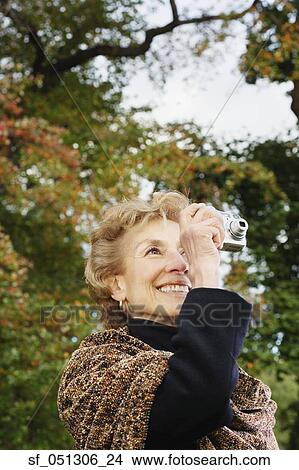 Senior woman taking photograph outdoors View Large Photo Image Picture - Senior woman taking photograph outdoors. Fotosearch