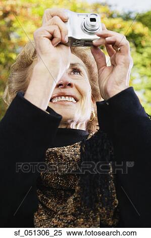 Stock Photography - Senior woman taking photograph outdoors. Fotosearch