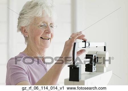 Senior woman weighing self on scale View Large Photo Image Stock Image - Senior woman weighing self on scale. Fotosearch