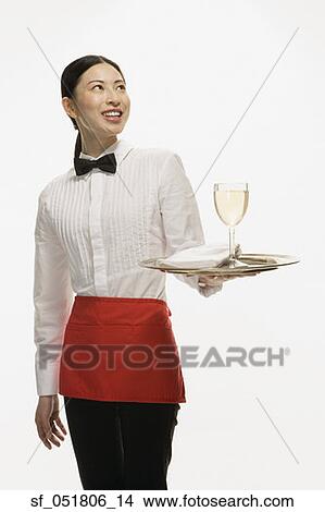 Picture - Studio shot of Asian waitress holding tray with wine glass. Fotosearch