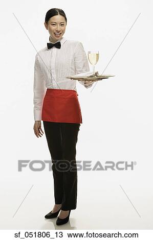 Stock Image - Studio shot of Asian waitress holding tray with wine glass. Fotosearch