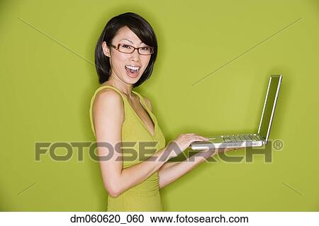 Stock Image - Studio shot of Asian woman smiling with laptop. Fotosearch