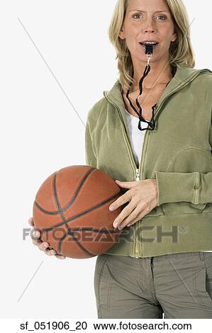 Stock Image - Studio shot of woman with whistle and basketball. Fotosearch