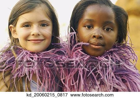 Stock Photo - Two young girls wearing feather boa and smiling. Fotosearch