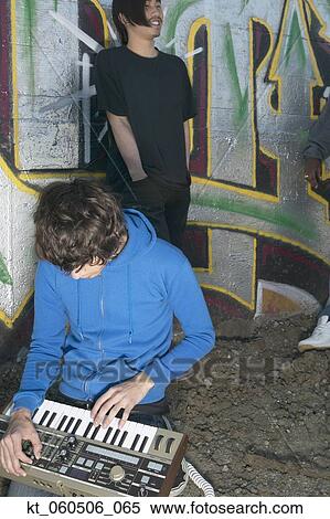 Two young men with music equipment next to graffitied wall View Large Photo Image Stock Photography - Two young men with music equipment next to graffitied wall. Fotosearch