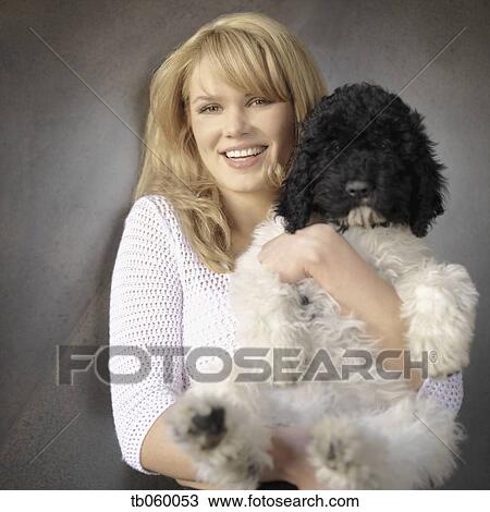 Stock Image - Woman holding dog and smiling. Fotosearch