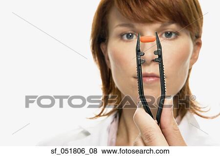 Woman holding pill in large tweezers View Large Photo Image Stock Photo - Woman holding pill in large tweezers. Fotosearch
