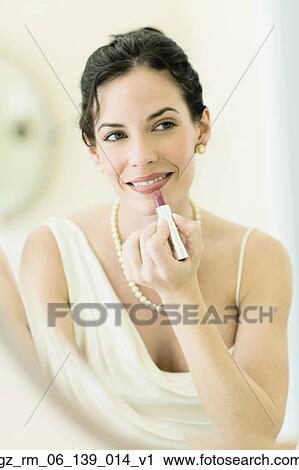Stock Image - Woman in fancy clothing applying lipstick. Fotosearch