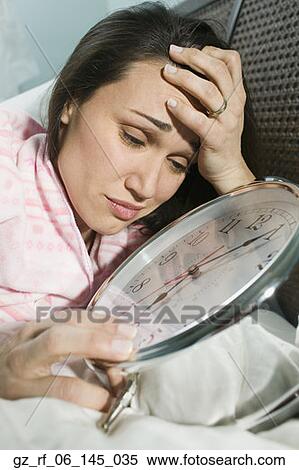 Woman laying in bed with giant alarm clock View Large Photo Image Stock Photography - Woman laying in bed with giant alarm clock. Fotosearch
