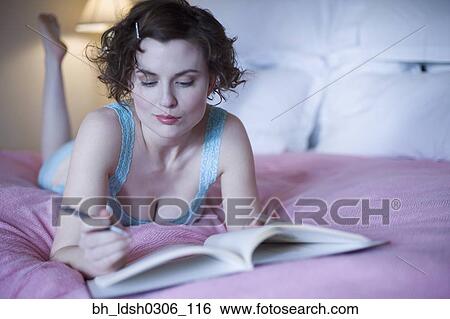 Woman laying on bed with pen and book View Large Photo Image Stock Photograph - Woman laying on bed with pen and book. Fotosearch