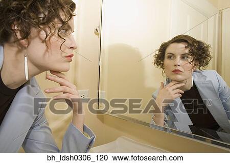 Woman looking in mirror with hand on chin View Large Photo Image Stock Image - Woman looking in mirror with hand on chin. Fotosearch