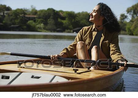 Stock Image - Woman sitting in canoe holding oar. Fotosearch