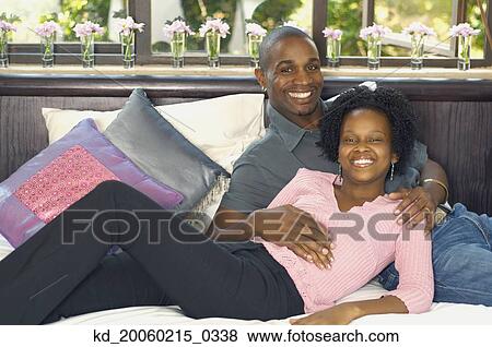 Stock Photo - Young African couple smiling on bed. Fotosearch