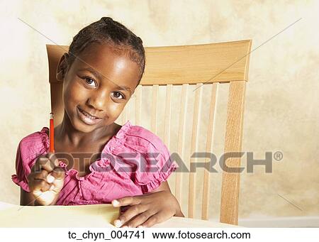 Stock Image - Young African girl holding pencil and smiling. Fotosearch
