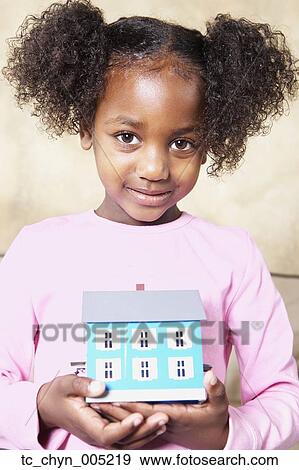Young African girl holding tiny house View Large Photo Image Stock Photo - Young African girl holding tiny house. Fotosearch