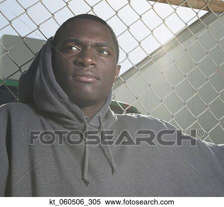 Young African man leaning against metal fence View Large Photo Image Stock Photography - Young African man leaning against metal fence. Fotosearch