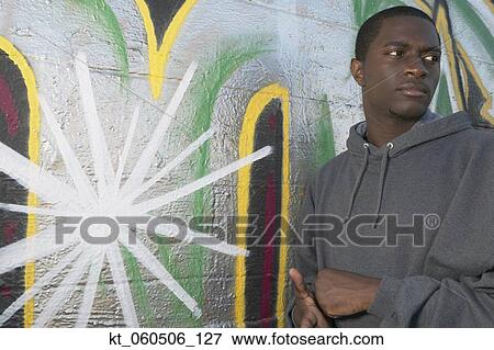 Young African man leaning on graffitied wall View Large Photo Image Stock Photo - Young African man leaning on graffitied wall. Fotosearch