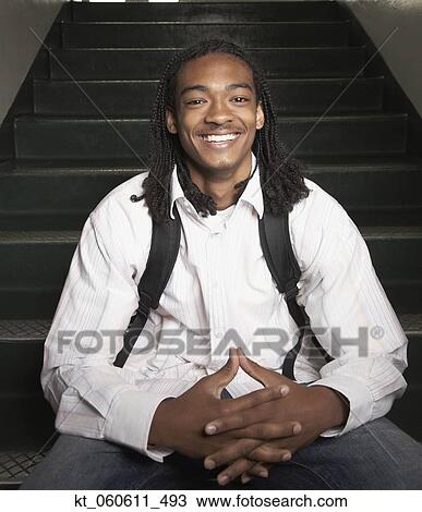 Young African man with backpack sitting on stairs View Large Photo Image Stock Image - Young African man with backpack sitting on stairs. Fotosearch