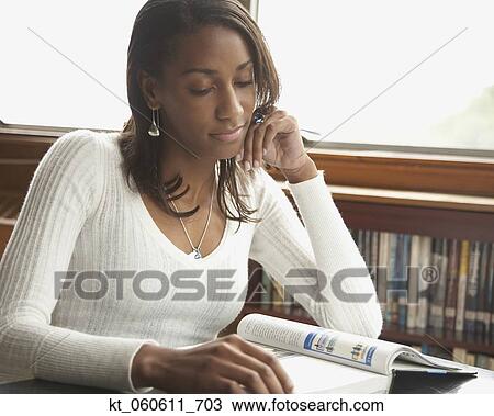 Stock Image - Young African woman reading text book. Fotosearch