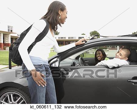 Stock Image - Young African woman talking to friends in car. Fotosearch