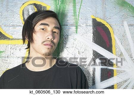 Young Asian man leaning against graffitied wall View Large Photo Image Stock Image - Young Asian man leaning against graffitied wall. Fotosearch
