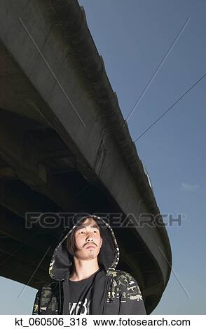 Young Asian man standing under raised highway View Large Photo Image Stock Photo - Young Asian man standing under raised highway. Fotosearch