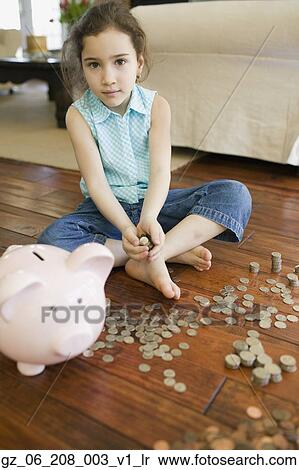 Stock Photography - Young girl counting money next to piggy bank. Fotosearch