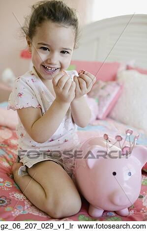 Stock Photography - Young girl putting money in piggy bank. Fotosearch