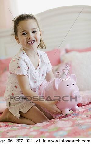 Young girl with piggy bank on bed View Large Photo Image Stock Photography - Young girl with piggy bank on bed. Fotosearch