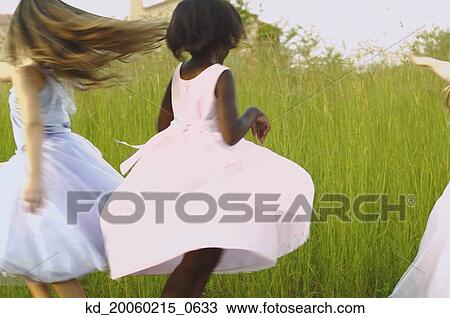Young girls wearing party dresses and playing in field View Large Photo Image Stock Image - Young girls wearing party dresses and playing in field. Fotosearch