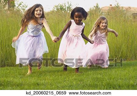 Young girls wearing party dresses and running in field View Large Photo Image Stock Photo - Young girls wearing party dresses and running in field. Fotosearch