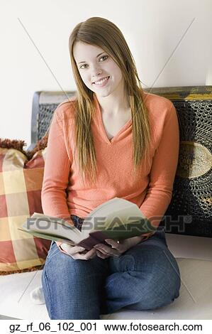 Stock Image - Young woman sitting on floor reading. Fotosearch
