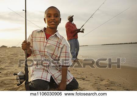 Stock Photograph - African father and son on beach with fishing gear. Fotosearch