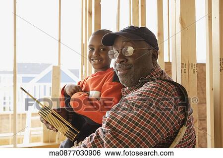 Stock Photograph - African man and young boy inside construction site. Fotosearch