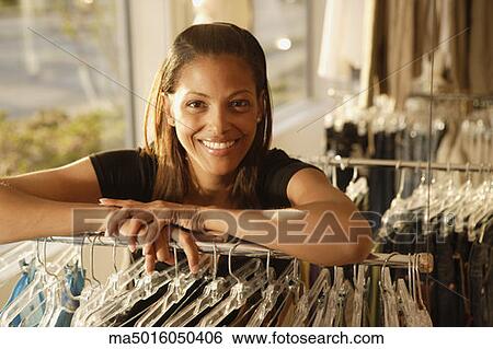 Stock Photograph - African woman leaning on rack at clothing store. Fotosearch