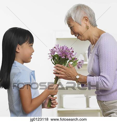 Asian girl giving grandmother bouquet of flowers View Large Photo Image Stock Photo - Asian girl giving grandmother bouquet of flowers. Fotosearch